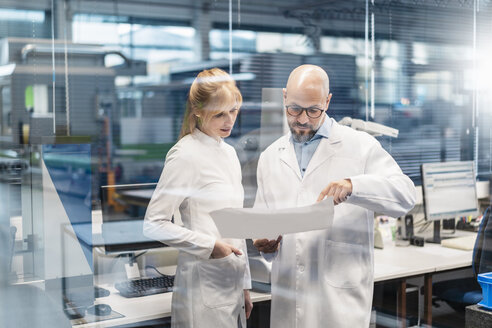 Two technicians wearing lab coats looking at plan - DIGF06208