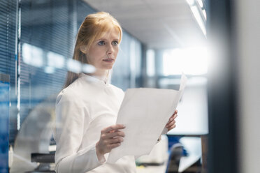 Woman wearing lab coat holding plan - DIGF06212