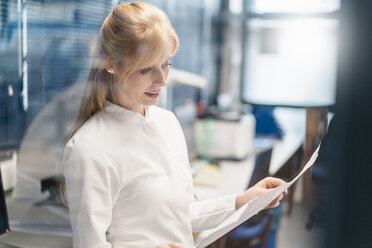 Woman wearing lab coat looking at plan - DIGF06213