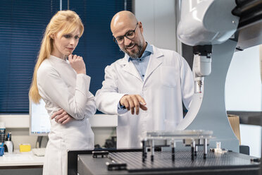 Two technicians wearing lab coats standing at machine - DIGF06216
