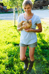 Woman carrying hen in countryside, Sonthofen, Bayern, Germany - CUF49891