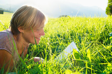 Woman reading book on grass in countryside, Sonthofen, Bayern, Germany - CUF49898