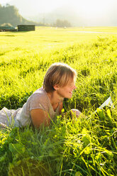 Woman reading book on grass in countryside, Sonthofen, Bayern, Germany - CUF49899