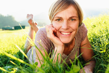 Woman lying down on grass in countryside - CUF49901