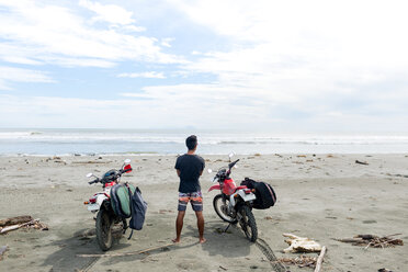 Motorradfahrer mit Surfbrett am Sandstrand, Abulug, Cagayan, Philippinen - CUF49915