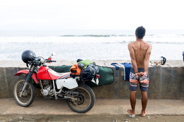 Surfer auf dem Motorrad, der sich an der Meereswand streckt, Pagudpud, Ilocos Norte, Philippinen - CUF49933