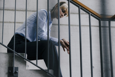 Erschöpfte Geschäftsfrau auf der Treppe sitzend - JOSF03147