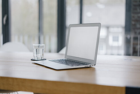 Laptop auf dem Schreibtisch im Büro mit einem Glas Wasser - JOSF03176