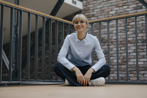 Relaxed businesswoman sitting cross-legged on the floor - JOSF03189