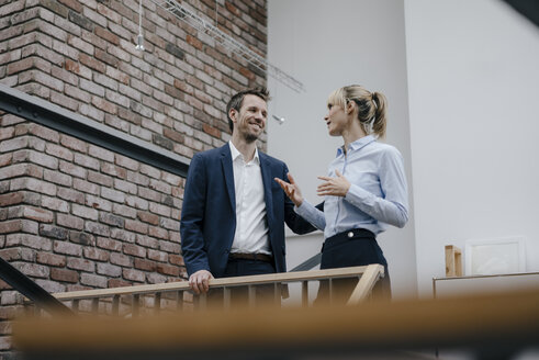 Businessman and woman standing in office building, discussing - JOSF03190