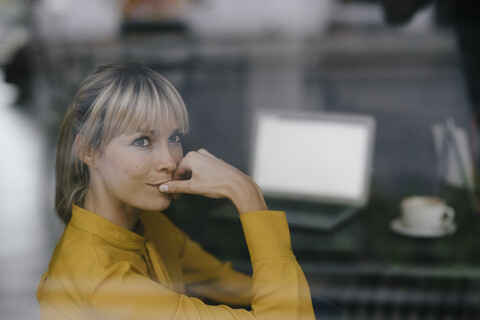 Blonde Geschäftsfrau sitzt am Fenster und denkt nach, lizenzfreies Stockfoto