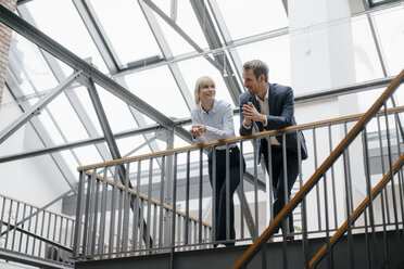 Businessman and woman standing in office building, discussing - JOSF03200