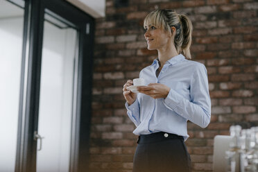 Geschäftsfrau im Büro stehend, macht eine Pause, trinkt Kaffee - JOSF03204