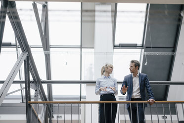 Businessman and woman standing in office building, discussing - JOSF03206