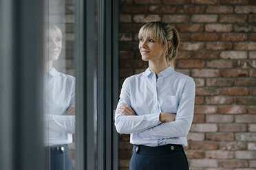 Confident businesswoman looking out of window, with arms crossed - JOSF03208