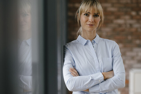 Porträt einer blonden Geschäftsfrau mit verschränkten Armen, lizenzfreies Stockfoto