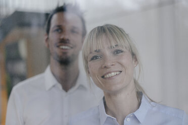 Erfolgreiche Geschäftsfrau und Geschäftsmann schaut aus dem Fenster, lächelnd - JOSF03227