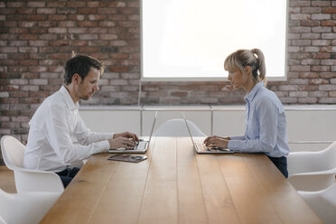 Geschäftsmann und Frau sitzen am Schreibtisch und arbeiten am Laptop - JOSF03236