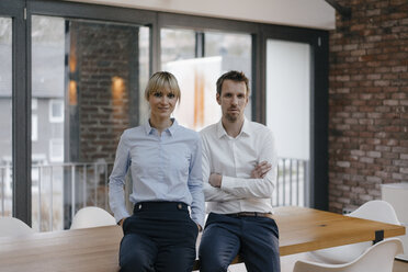 Successful businessman and woman standing in office, with arms crossed - JOSF03242