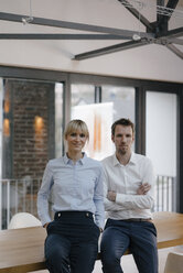 Successful businessman and woman standing in office, with arms crossed - JOSF03243