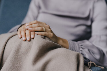 Folded hands of a woman on a blanket over her knees - JOSF03267