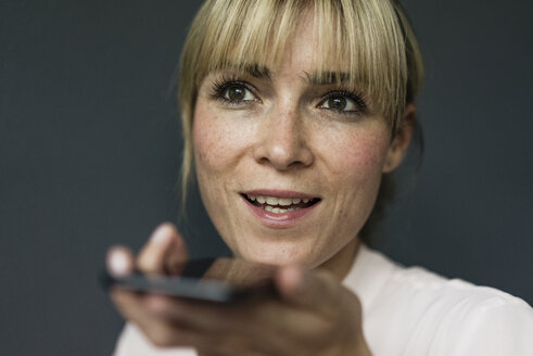 Porträt einer blonden Geschäftsfrau, die ein Smartphone benutzt - JOSF03273