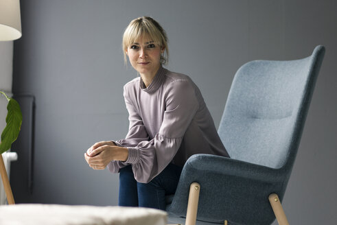 Blond woman sitting in armchair, looking at camera - JOSF03276