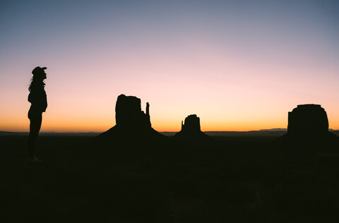 USA, Utah, Monument Valley, Silhouette einer Frau mit Cowboyhut bei Sonnenaufgang, lizenzfreies Stockfoto