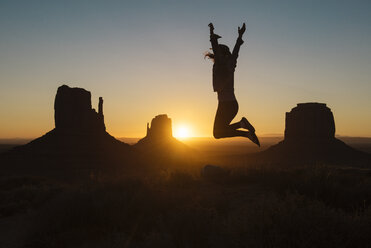 USA, Utah, Monument Valley, Silhouette einer glücklichen Frau, die bei Sonnenaufgang in die Luft springt - GEMF02887