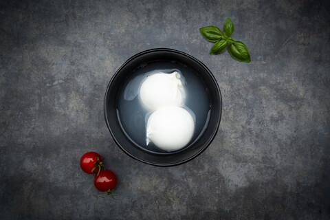 Tomaten, Basilikumblätter und Burrata in der Schüssel, von oben, lizenzfreies Stockfoto