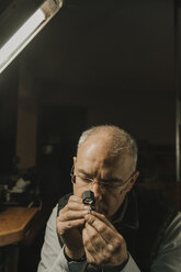 Kunsthandwerker beim Betrachten eines Rings mit Edelstein, Porträt - AHSF00009