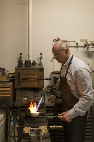 Kunsthandwerker bei der Herstellung von Schmuck in seiner Werkstatt, lizenzfreies Stockfoto
