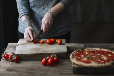 Junge Frau bereitet Pizza vor, schneidet Tomaten auf einem Schneidebrett - ALBF00801