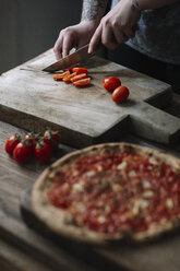 Junge Frau bereitet Pizza vor, schneidet Tomaten auf einem Schneidebrett - ALBF00803