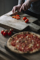 Young woman preparing pizza, cutting tomatoes on chopping board - ALBF00803