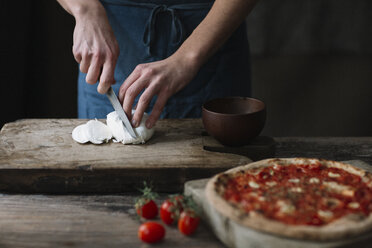 Junger Mann bereitet Pizza vor, schneidet Mozzarella auf einem Schneidebrett - ALBF00805
