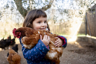 Portrait of smiling toddler girl holding chicken - GEMF02905