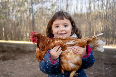 Portrait of happy toddler girl holding chicken - GEMF02906