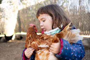 Mädchen im Kleinkindalter spricht mit Huhn auf ihren Armen - GEMF02907