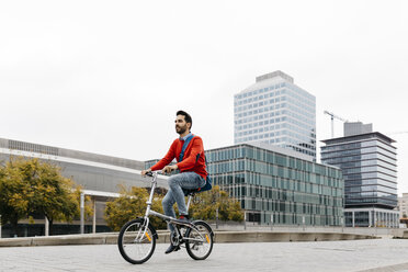 Casual businessman commuting in the city, using his folding bike - JRFF02818