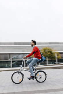 Casual businessman commuting in the city, using his folding bike - JRFF02821