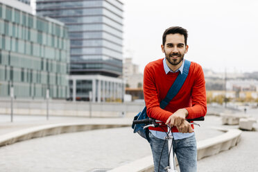 Casual businessman commuting in the city, using his folding bike - JRFF02823