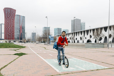 Casual businessman commuting in the city, using his folding bike - JRFF02844