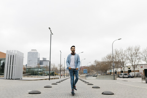 Mann beim Pendeln in der Stadt, der sein Kickboard benutzt, lizenzfreies Stockfoto