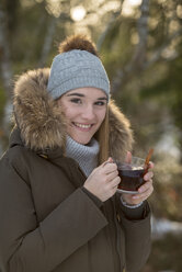 Porträt einer lächelnden jungen Frau beim Teetrinken im Winter - LBF02435