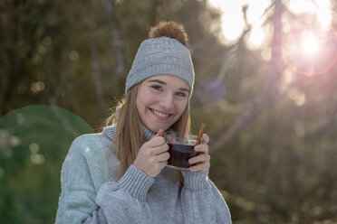 Porträt einer lächelnden jungen Frau mit einer Tasse Tee im Wald - LBF02437