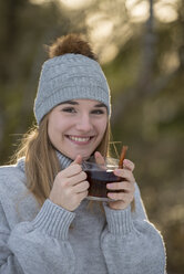 Porträt einer glücklichen jungen Frau mit einer Tasse Tee im Wald - LBF02438