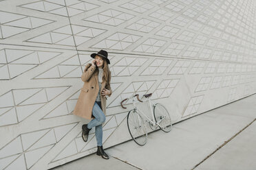 Junge Hipster-Frau, die in der Nähe eines Fahrrads telefoniert - AHSF00054