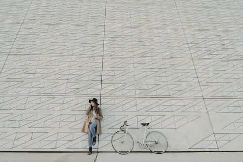 Junge Hipster-Frau, die in der Nähe eines Fahrrads telefoniert - AHSF00055