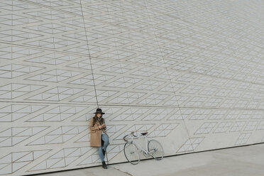 Young hipster woman holding smartphone near to a bicycle - AHSF00057